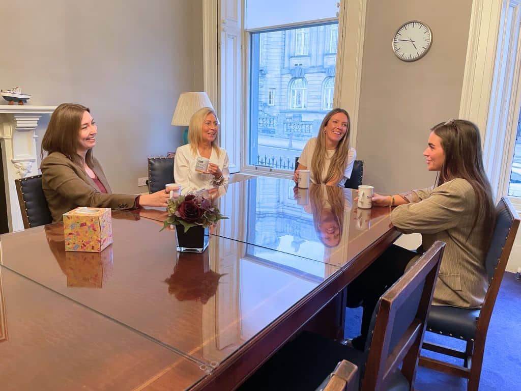 Scullion LAW staff gathered around a table at their Hamilton office, discussing and celebrating women's achievements for International Women's Day.